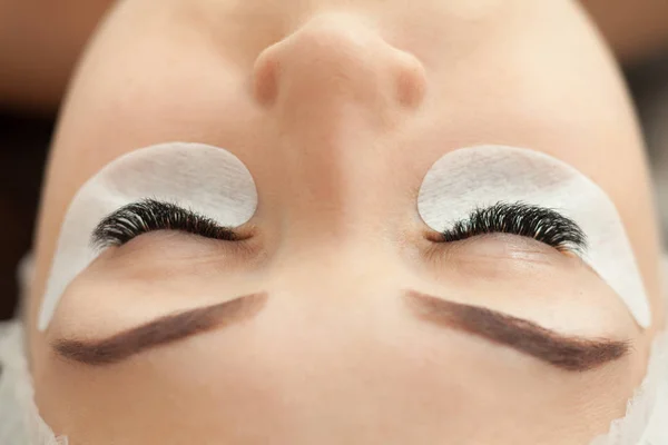 Female face with long eyelashes, close-up. Eyelash extensions prosedure