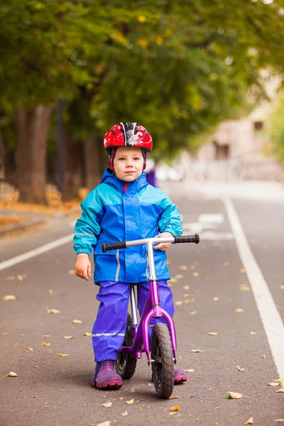 Хлопчик в теплій куртці сидить на своєму балансовому велосипеді — стокове фото