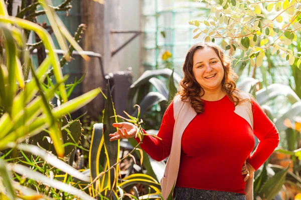 Young specialist in botanical garden show on the plant — Stockfoto