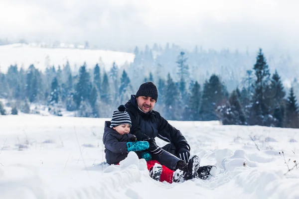 Vader en zoon spelen met sneeuw in de natuur — Stockfoto