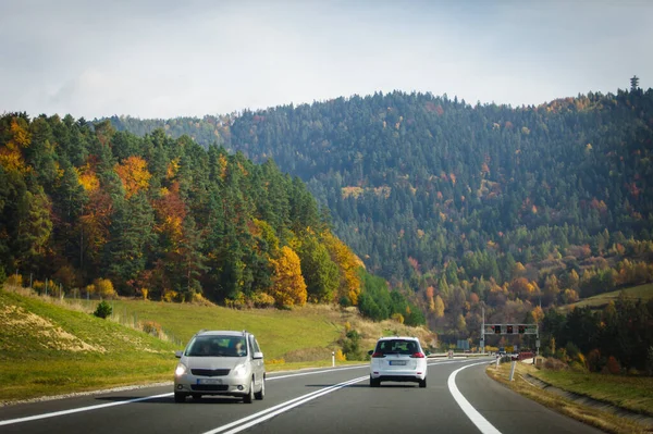 Cars driving on the asphalt road passing through the mountain — Stok fotoğraf