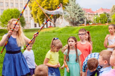 Woman making for kids big soap bubble