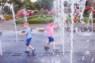 Two guys enjoy cool water in a fountain