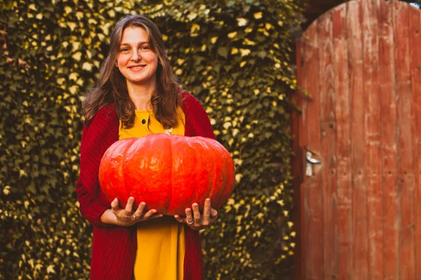 Cheerful woman with big pumpkin in the hands at the farm — Stockfoto