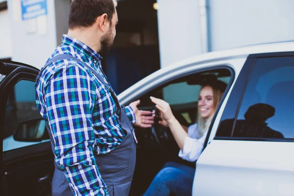 Car service worker taking car keys of woman for providing technical assistance of car