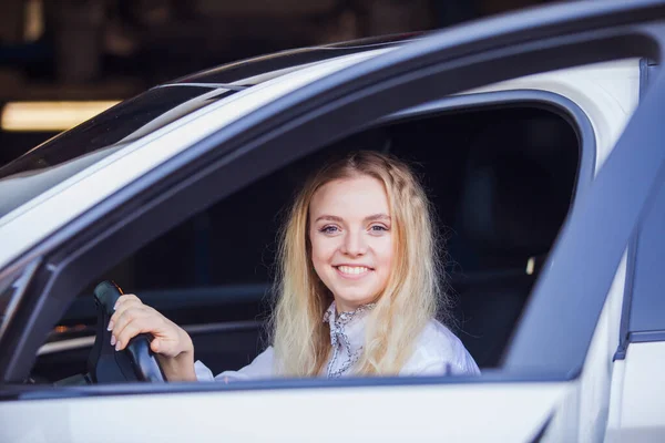Kobieta kierowca siedzi w białym samochodzie, uśmiechnięta — Zdjęcie stockowe