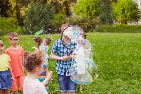 Pojke med vänner gör stora såpbubblor utomhus — Stockfoto