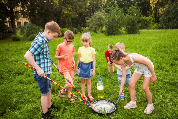 Little friends training to make big soap bubbles on a meadow — Stock Photo, Image