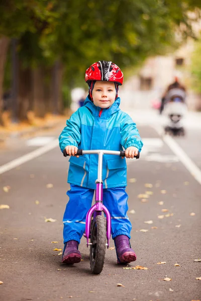 Хлопчик в теплій куртці сидить на своєму балансовому велосипеді — стокове фото