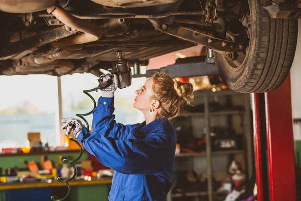Joven mecánico trabaja debajo del coche — Foto de Stock