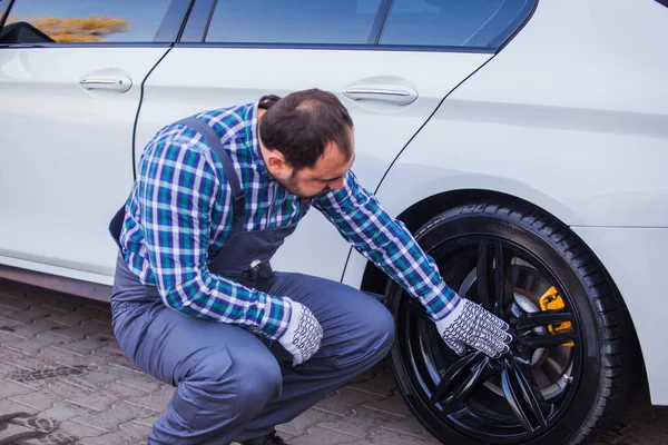 Trabajador de servicio de neumáticos haciendo trampas en una rueda de coche — Foto de Stock