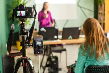 Professional camera is recording seminar with optional accessory. Woman making presentation, lection or meeting.