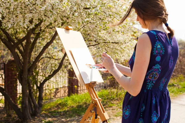 Καλλιτέχνης ζωγραφίζει μια εικόνα της ανθισμένης κερασιάς στον κήπο. — Φωτογραφία Αρχείου