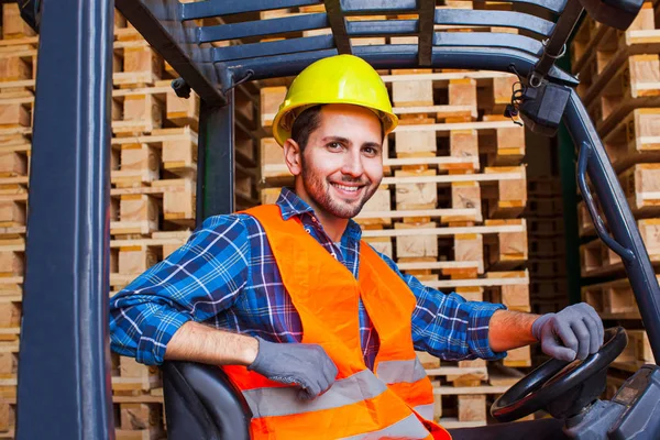 Όμορφος χαμογελαστός εργάτης που οδηγεί κλαρκ στην αποθήκη. Έννοια της βιομηχανίας ξύλου. — Φωτογραφία Αρχείου