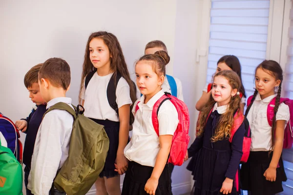 School children in uniform with backpacks going to class — ストック写真