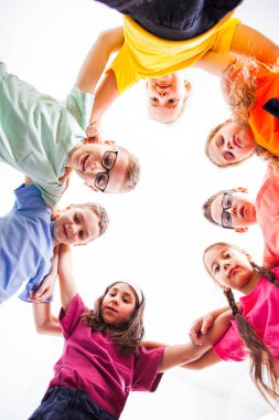 Below view of children embracing each other and smiling at camera.