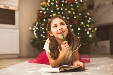 Happy girl dreaming about best gift for Christmas