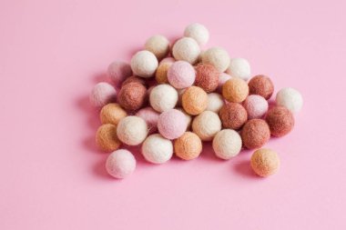 Pale of soft wool balls on pink background