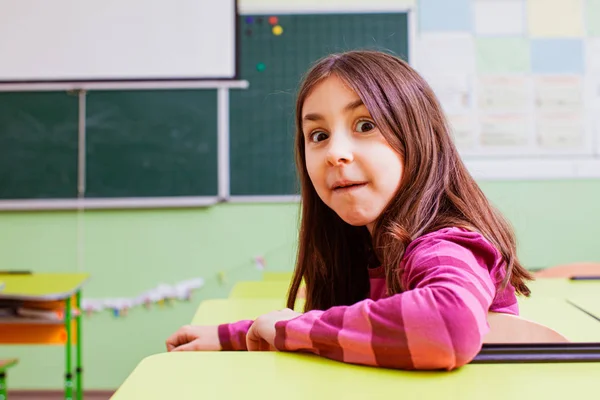 Roztomilá dívka s legrační tvář v prázdné třídě — Stock fotografie