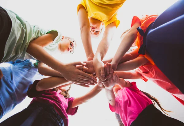 Muitas crianças empilhando as mãos juntas. Símbolo de trabalho em equipe e motivação . — Fotografia de Stock