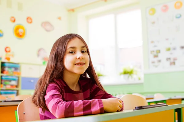 Счастливая улыбающаяся девушка сидит в своем классе — стоковое фото