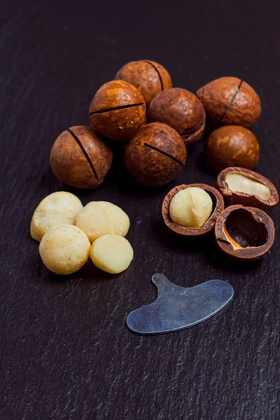 Bio-Macadamia-Nüsse auf schwarzem Schieferhintergrund, Nahaufnahme. — Stockfoto