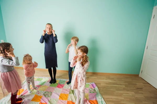 Children copy the teacher and touch their ears, learning body parts. — Stock Photo, Image