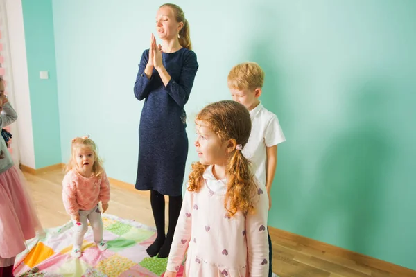 Little girl enjoying game with friends and teacher in kindergarden. Happy and healthy childhood. — Stock Photo, Image