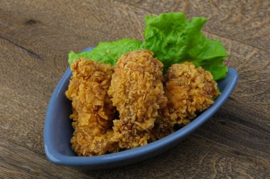 Çıtır tavuk kanatları ile salata yaprakları üzerinde ahşap arka plan