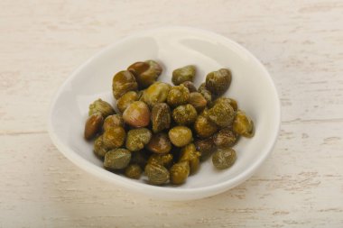 Kase ahşap arka plan üzerinde turşu Kapari