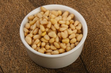 Sedir fındık yığın içinde kase ahşap arka plan üzerinde