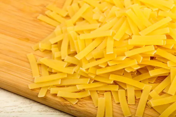 Raw pasta on wooden board — Stock Photo, Image