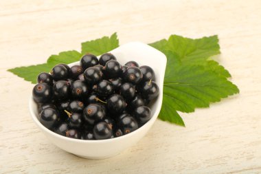 Olgun siyah kuş üzümü ile yaprak kase