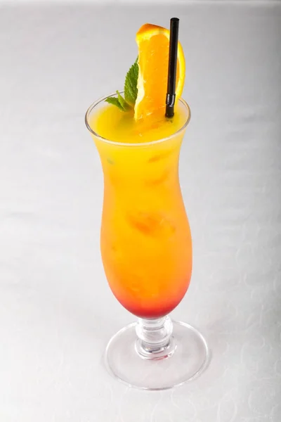 Tequila Sunrise cocktail with orange over wooden background