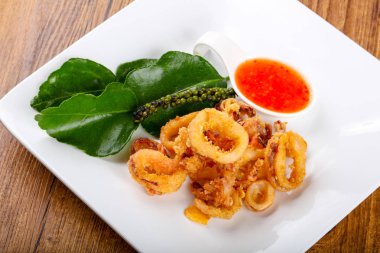 Kızarmış kalamar halkaları ahşap arka plan üzerinde acı baharatlı sos ile