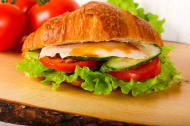 Kruvasan tavuk ve ahşap arka plan üzerinde domates ile