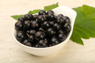 Olgun siyah kuş üzümü yaprağı, ahşap masa arka plan ile kase