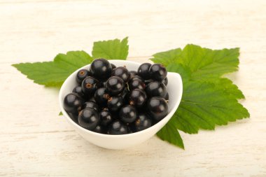 Olgun siyah kuş üzümü yaprağı, ahşap masa arka plan ile kase