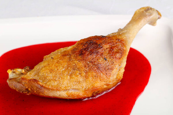 Duck leg in berry sauce on white plate