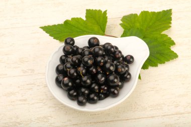 Olgun siyah kuş üzümü yaprağı, ahşap masa arka plan ile kase