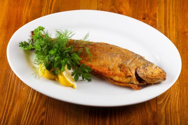 Kızarmış alabalık limon ve otlar ahşap arka plan üzerinde servis