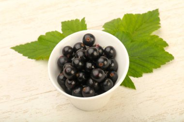 Olgun siyah kuş üzümü yaprağı, ahşap masa arka plan ile kase