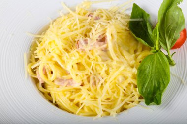 Makarna Carbonara fesleğen yaprakları beyaz tabak içinde hizmet