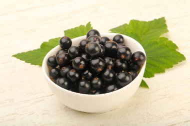 Olgun siyah kuş üzümü yaprağı, ahşap masa arka plan ile kase