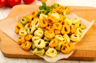Fesleğenli - ahşap arka plan üzerinde yemek pişirmek için hazır çiğ tortellini