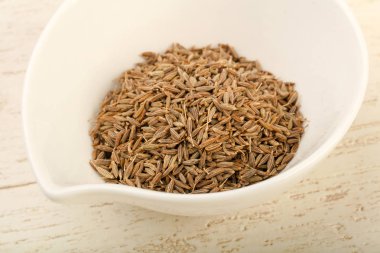 Kimyon tohumları yığın ahşap arka plan üzerinde beyaz kase