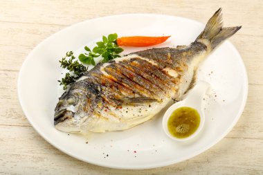 Izgara dorado balık sosu, kekik ve fesleğen ahşap arka plan üzerinde