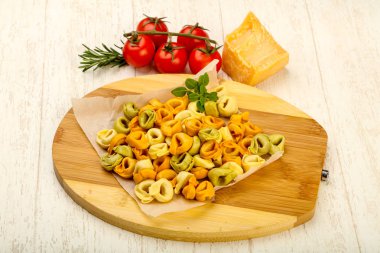 Fesleğenli - ahşap arka plan üzerinde yemek pişirmek için hazır çiğ tortellini