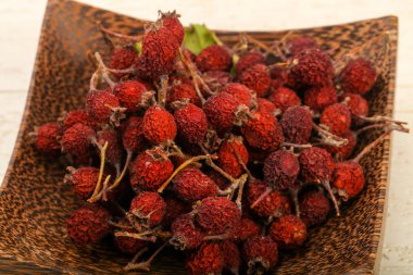 Kase ahşap arka plan üzerinde kuru alıç yığın 