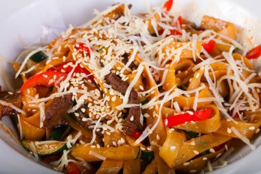 Beyaz tabakta sığır eti ve parmesan peynirli makarna